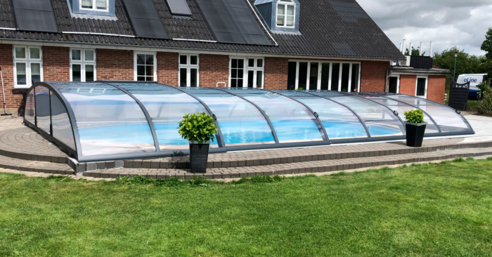 Nova Polaris skydetag installeret over oval pool i Midtjylland. Dette pool tag kan skydes som teleskop og den høje bue gør det muligt at bade, mens det er lukket.