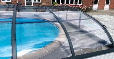 Skydetag på oval udendørs swimmingpool Midtjylland|Nova Polaris pooltag installeret over oval swimmingpool i midtjylland. Taget er med mellemhøj bue, så der sagtens kan svømmes imens, der er lukket.|Høj bue på Nova Polaris skyde-pooltag installeret i Midtjylland. Derved kan der sagtens svømmes, selvom overdækningen er lukket.|Nova Polaris skydetag installeret over oval pool i Midtjylland. Dette pool tag kan skydes som teleskop og den høje bue gør det muligt at bade, mens det er lukket.