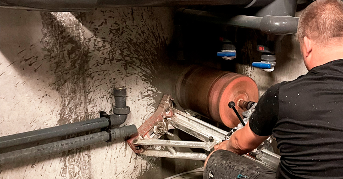 Tekniker borer stort hul i forbindelse med skade i væggen, der holder dyseledning under 50 m bassin hos Kildeskovhallen. Sikring af vandkvalitet.