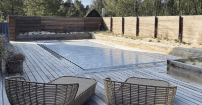 Neutralt lamelcover dækker udendørspool placeret foran nybygget sommerhus. PP poolen under har overløbsrender af kantsten med huller. Luksuriøst feriehus.|Støbning af bundplade til swimmingpool ved nybygget luksuriøst feriehus hvor terrassen får etableret terrasse med pp pool - udgravning.|PP-pool leveres opret på ladet af lastbil. Et helstøbt bassin, der nedsænkes i udgravning med kran. Her lige ankommet til sommerhus.|Lastbil leverer PP-Pool. Pladsen er snæver i Blåvand, men stort luksuriøst byggeprojekt kræver store køretøjer med kran.|pp-pool i luften. Levering af formstøbt swimmingpool til luksuriøst sommerhus ved vestkysten. Bassinet er støbt i polystone plast og isoleret.|PP bassin leveres med kran|Placering af swimmingpool med kran. En PP pool leveres her med kran og skal nedsænkes i terrasse foran luksuriøst sommerhus.|Placering af PP-pool ved et luksuriøst feriehus i Blåvand. Poolen er støbt i prolypropylen og leveres fuldisoleret til nedsænkning|Støbning af pp bassin ved sommerhus i Blåvand.|PP pool overløbsrende af sten. Eksklusiv afslutning på en swimmingpool med højt vandspejl. Lader vandet forsvinde i en naturlig krans af kantflise.|Overløb af sten. Specialudskåret sten har givet swimmingpoolens overløbsrende et helt unikt og eksklusivt look.|Færdigt pp pool projekt med træterrasse, vand i swimmingpoolen og en flot tilskåret overløbsrende af fliser.|Overløbsrende i flisemateriale. Der er udskåret huller til at vandet kan løbe ud gennem fliserne for at blive renset.|Overløbsrende af kantflise. Flotte friser i kantfliserne giver et unikt og eksklusivt look ved den installerede PP-pool omkranset af træterrasse.|Lamel cover i feriehus dækker her over en nybygget swimmingpool i Blåvand. Overdækningen giver tryghed og sikrer vandet fra snavs.|Swimmingpool med lameloverdækning. To billeder af det smukke luksuriøse feriehus og pool med lysegrå lamelcover