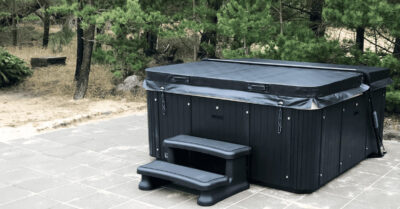 Terrasse med MaXXwell Laidback udespa. Stor, sort og flot placeret ved dertil egnet sommerhus terrasse.|MaXXwell udespa leveres med kran. Model Laidback spabade designet for sommerhuse, hvor mange forskellige gæster huser spaen.|Levering af svømmespa. Flyvende gods henover hustag. Spaen leveres med kran til husets terrasse, hvor den skal integreres.|Levering af en MaXXwell Laidback udespa i luften. Per normalvis kranes disse spa ind, hvis den skal på husets terrasse. Det er også tilfældet her.